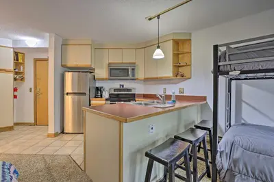a kitchen with a sink and a counter with two bar stools at Iron Horse Studio with Resort Amenities Walk to WP! in Winter Park