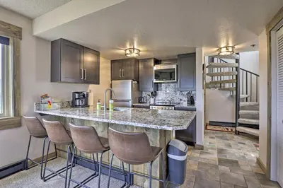 a kitchen with a large counter with bar stools at Updated Studio Loft in Granby Epic Mountain Views in Granby