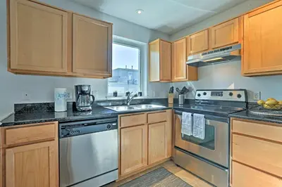 a kitchen with wooden cabinets and stainless steel appliances at LoHi Apartment with Patio 1 Mi to Downtown Denver! in Denver