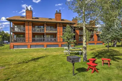a house with a picnic table and red chairs in front of it at Walk to Main St Frisco Condo with Community Pool! in Frisco