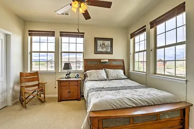 a bedroom with a bed and a desk and windows at 18 Mi to Winter Park Granby Condo with Covered Deck in Granby