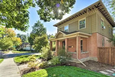 a house with a fence in a yard at Historic Apartment - Walk to CSU Campus and Old Town in Fort Collins