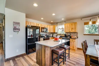 a kitchen with wooden cabinets and a black refrigerator at Newly Built Estes Park Townhome, 2 Miles to RMNP! in Estes Park