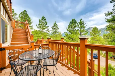 a wooden deck with a table and chairs on it at Estes Park Condo with Deck and Views about 3 Miles to RMNP in Estes Park