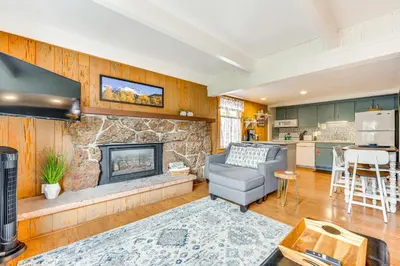 a living room with a fireplace and a gray couch at Estes Park Condo with Deck and Views about 3 Miles to RMNP in Estes Park