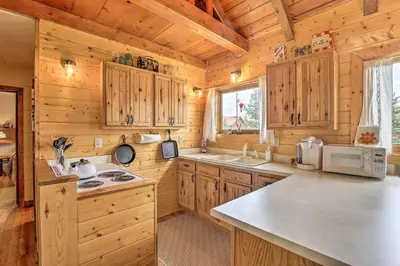 a kitchen with wooden cabinets and a counter top at Walk to Grand Lake Historic Dtwn Cabin! in Grand Lake