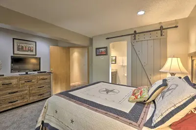 a bedroom with a bed with a television and a barn door at Creekside Frisco Condo with Views and Pool Access! in Frisco