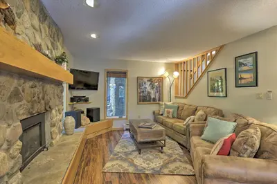 a living room with a couch and a stone fireplace at Creekside Frisco Condo with Views and Pool Access! in Frisco