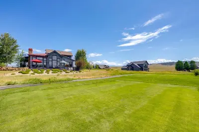 a golf course with a house and a green yard at Grand Elk Golf Club On-Site Mtn-View Home with Deck in Granby