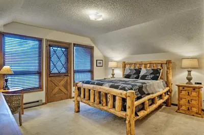 a bedroom with a wooden bed in a room with windows at Peaceful Pines Estes Park Home Longs Peak View in Estes Park