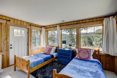 two beds in a room with windows at Charming Estes Park Cabin with 2 Private Patios! in Estes Park