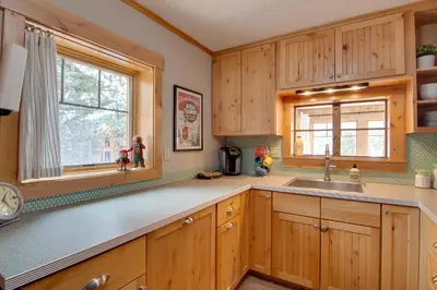 a kitchen with wooden cabinets and a sink and a window at Charming Estes Park Cabin with 2 Private Patios! in Estes Park