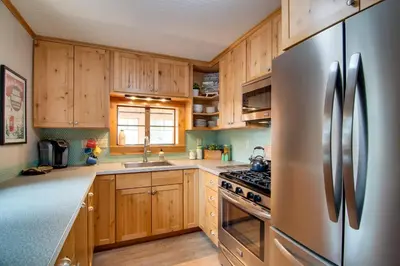 a kitchen with wooden cabinets and a stainless steel refrigerator at Charming Estes Park Cabin with 2 Private Patios! in Estes Park