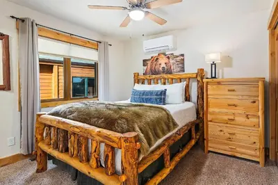 a bedroom with a wooden bed and a ceiling fan at Updated and Spacious Lodge in Heart of Estes Park! in Estes Park
