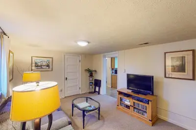 a living room with a flat screen tv and a table at Elati Guesthouse Walkable Home in Arts District in Denver