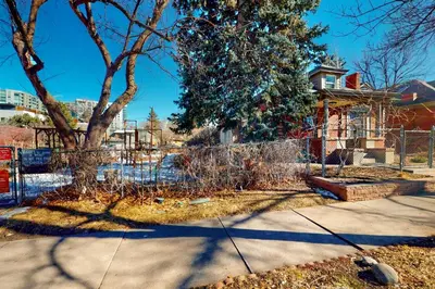 a fence in front of a house with a tree at Elati Guesthouse Walkable Home in Arts District in Denver