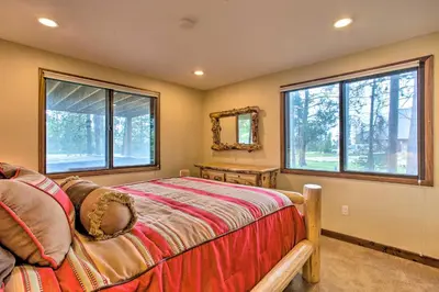 a bedroom with a bed and two windows at Sprawling Fraser Cabin with Private Hot Tub and Deck! in Fraser