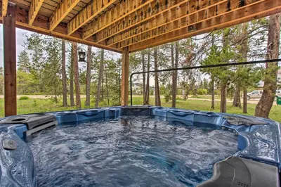 a hot tub in the middle of a pavilion with trees at Sprawling Fraser Cabin with Private Hot Tub and Deck! in Fraser