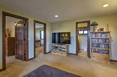 a living room with a flat screen tv and book shelves at Sprawling Fraser Cabin with Private Hot Tub and Deck! in Fraser