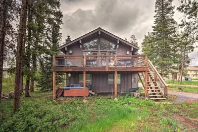 a house with a wrap around deck in the woods at Sprawling Fraser Cabin with Private Hot Tub and Deck! in Fraser