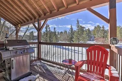 a patio with a grill and a red chair on a deck at Pet-Friendly Fraser Condo with Community Hot Tub in Fraser