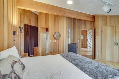 a bedroom with a bed and wooden walls at Panoramic Mountain-View Retreat with Hot Tub and Deck! in Tabernash