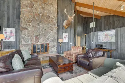 a living room with leather furniture and a stone wall at Panoramic Mountain-View Retreat with Hot Tub and Deck! in Tabernash