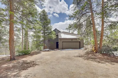 a house with a garage in the woods at Panoramic Mountain-View Retreat with Hot Tub and Deck! in Tabernash