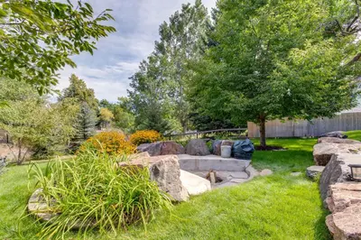 a garden with a stone bench in the grass at Modern Creekside Home 9 Mi to Downtown Denver in Lakewood