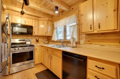 a kitchen with wooden cabinets and a stove and a sink at Picturesque Log Cabin in Estes Park 9 Mi to RMNP in Estes Park