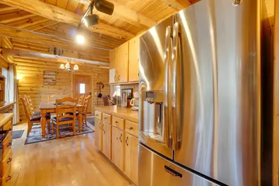 a kitchen with a stainless steel refrigerator and a table at Picturesque Log Cabin in Estes Park 9 Mi to RMNP in Estes Park