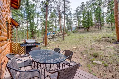 a table and chairs on a deck with a grill at Picturesque Log Cabin in Estes Park 9 Mi to RMNP in Estes Park