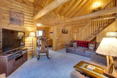 a living room with a couch and a television in a log cabin at Picturesque Log Cabin in Estes Park 9 Mi to RMNP in Estes Park