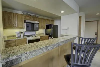 a kitchen with wooden cabinets and a counter with two chairs at 432 Marina Place condo in Dillon