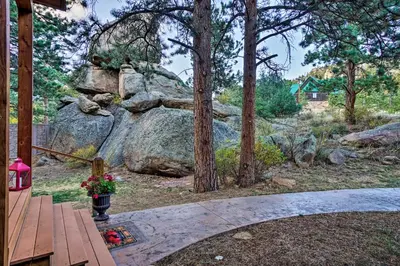 a backyard with a large rock and flowers on a porch at Fall River Hideaway in Estes - 3 Mi to Natl Park! in Estes Park