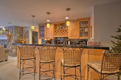 a kitchen with a bar with four stools at Fall River Hideaway in Estes - 3 Mi to Natl Park! in Estes Park