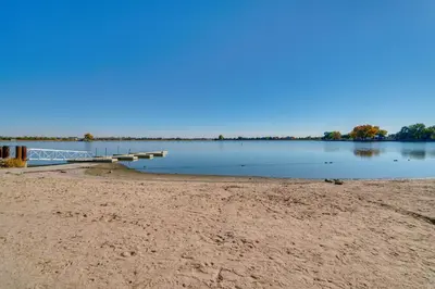 a sandy beach with a dock on a lake at Charming Getaway, Walk to Windsor Lake and Downtown! in Windsor