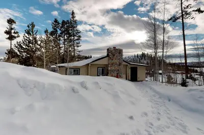 a house with a pile of snow in front of it at Grand Lake Cabin Escape in Grand Lake