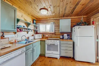 a kitchen with a white refrigerator and wooden walls at Grand Lake Cabin Escape in Grand Lake