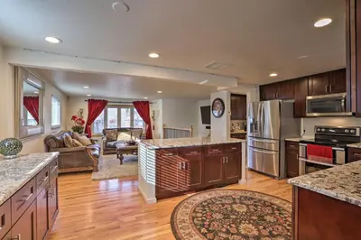 a large kitchen with wooden cabinets and a living room at Private Yard and Patio Denver Area Home! in Northglenn