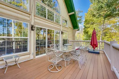 a patio with a table and chairs on a deck at Secluded Log Cabin with Game Room and Forest Views in Red Feather Lakes