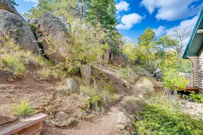 a dirt trail next to a house at Secluded Log Cabin with Game Room and Forest Views in Red Feather Lakes