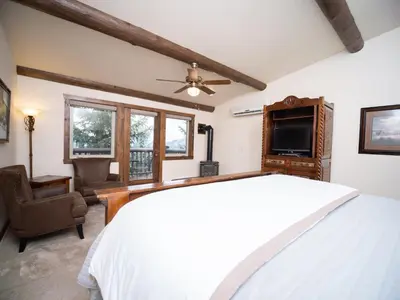 a bedroom with a white bed and a tv at Taharaa Mountain Lodge in Estes Park