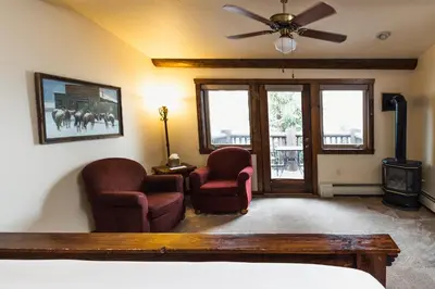 a living room with two chairs and a ceiling fan at Taharaa Mountain Lodge in Estes Park