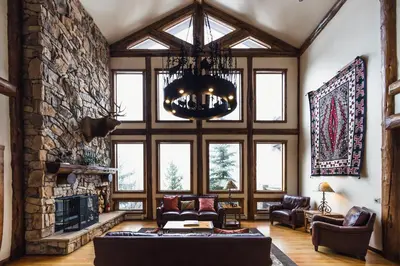 a living room with a large stone fireplace and a chandelier at Taharaa Mountain Lodge in Estes Park