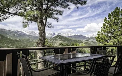 a table and chairs on a balcony with a view of mountains at Divine Destiny Luxury Home at Windcliff condo in Estes Park