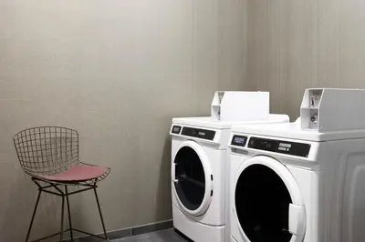 a washing machine and a chair in a room at Courtyard Denver Aurora in Aurora