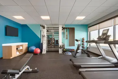 a gym with blue walls and tread machines at Avid Hotels - Denver Airport Area by IHG in Denver