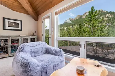 a living room with a chair and a large window at Wanderlust Luxury Vacation Home at Windcliff condo in Estes Park