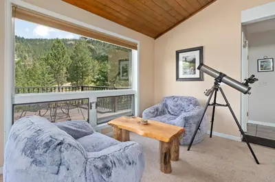 a living room with two chairs and a telescope at Wanderlust Luxury Vacation Home at Windcliff condo in Estes Park